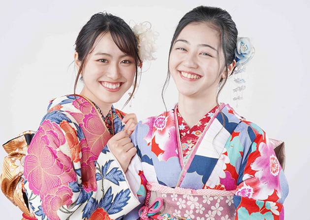 華やかな振袖を着て微笑む2人の女性