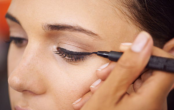 Closeup of a young woman getting liner applied to her eyes